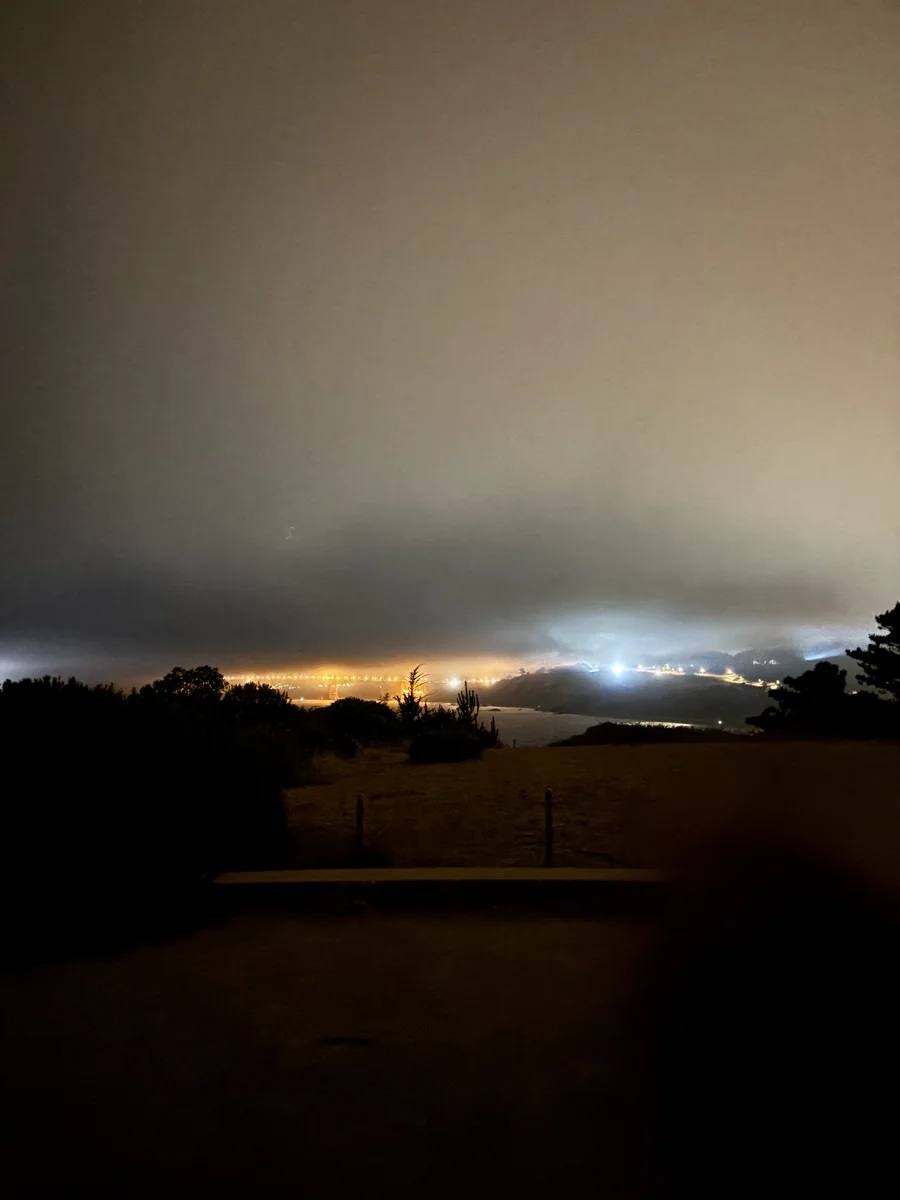 Golden Gate Bridge lights glowing beneath nighttime fog