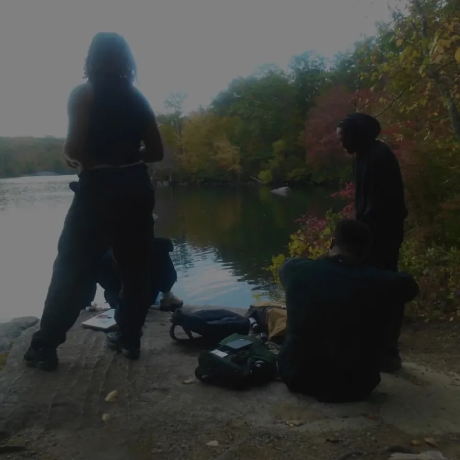 friends gathered on a lakeside rock at dusk